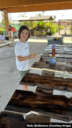 Philip, a young volunteer, coats wooden panels recovered from the house in a preservative solution.