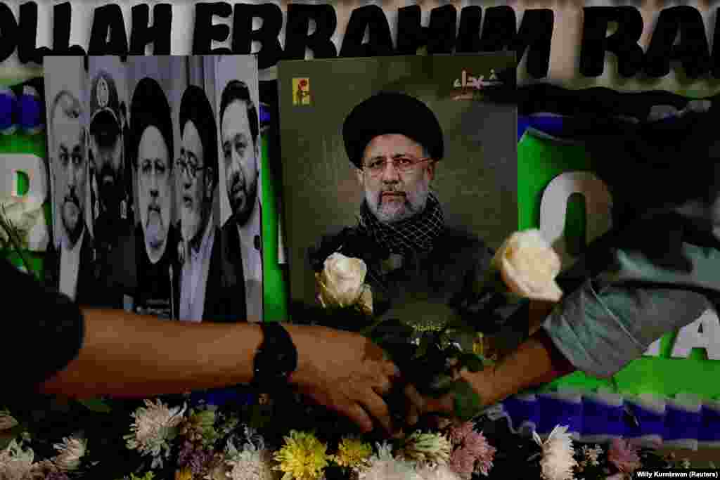 People lay flowers near pictures of Raisi during a vigil paying tribute to him and other victims outside the Iranian Embassy in Jakarta, Indonesia. European Council President Charles Michel said the European Union "expresses its sincere condolences."
