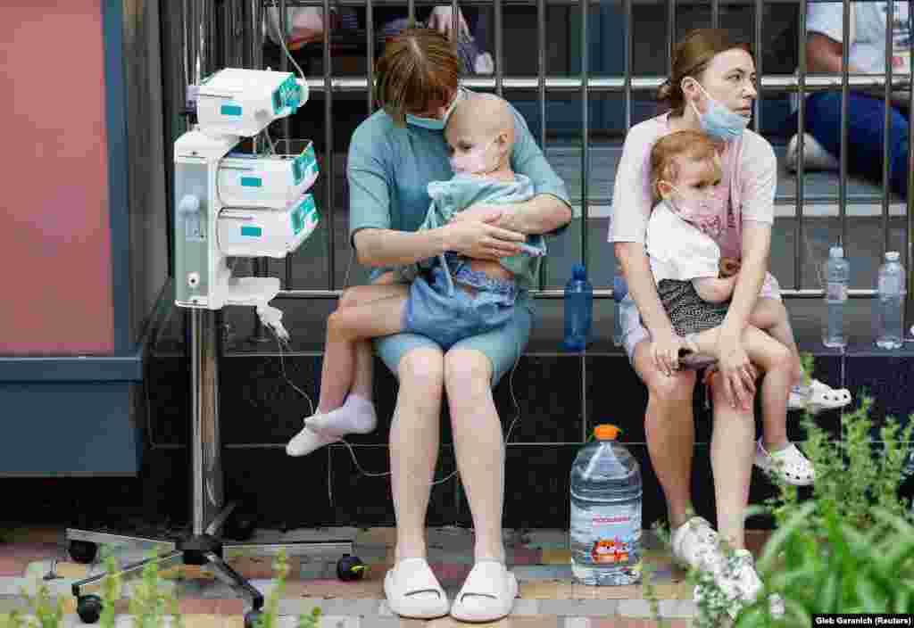 Women hold patients outside the damaged hospital. 