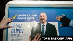 AZERBAIJAN - Electoral officials stick up a poster of Azerbaijani President Ilham Aliyev in Baku on January 15, 2024, on the first day of the official campaigning for the February 7 presidential election.