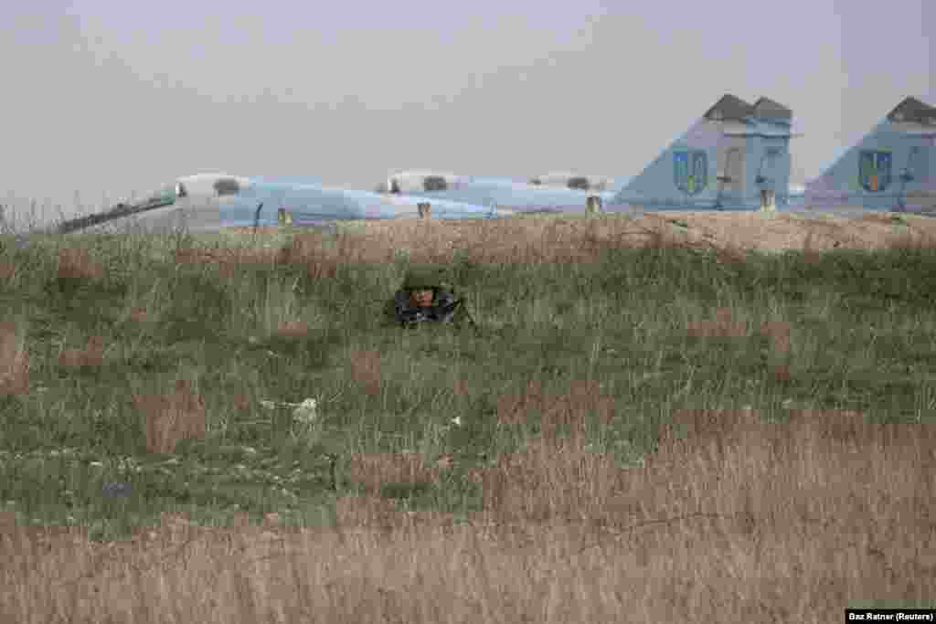 A Russian soldier watching Ukrainian military personnel at the Belbek airport, near Sevastopol. The Ukrainian Air Force base became one of the last Ukrainian holdouts in Crimea as its commander refused to hand over the site to Russian troops. He was eventually detained by Russian forces and Ukrainian personnel were forced out. 