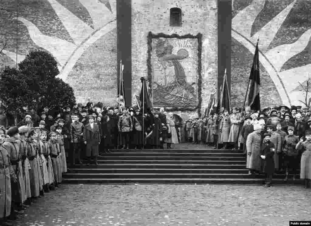 Большевики на открытии барельефа на стене Кремля. После большевистской революции 1917 года на месте нынешнего мавзолея установили барельеф в память о коммунистах, погибших во время революции 1917 года и похороненных в братских могилах у подножия кремлёвских стен. На этой фотографии, снятой в ноябре 1918 года, Владимир Ленин стоит практически на том же месте, где через несколько лет разместят его забальзамированное тело 
