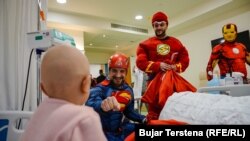 Berat Rexhepaj, i veshur në kostumin e Superman, viziton një fëmijë në repartin e Onkologjisë pediatrike në QKUK bashkë me vullnetarë të tjerë.