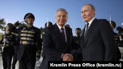 Uzbek President Shavkat Mirziyoev (left) greets Russian President Vladimir Putin at the airport in Tashkent on May 25.