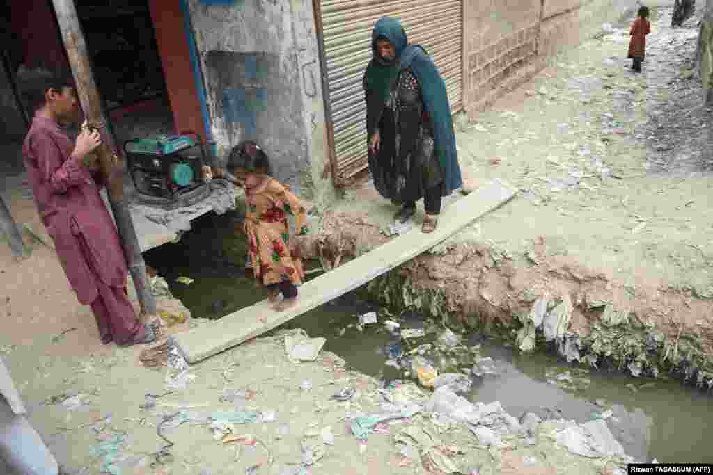 An Afghan girl and her mother cross an open sewer at a refugee camp in Karachi. Islamabad currently hosts about 1.4 million documented Afghan refugees. An equal number of undocumented Afghans are estimated to also be living in the country. 