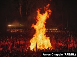 Crowds watch the bonfire grow.