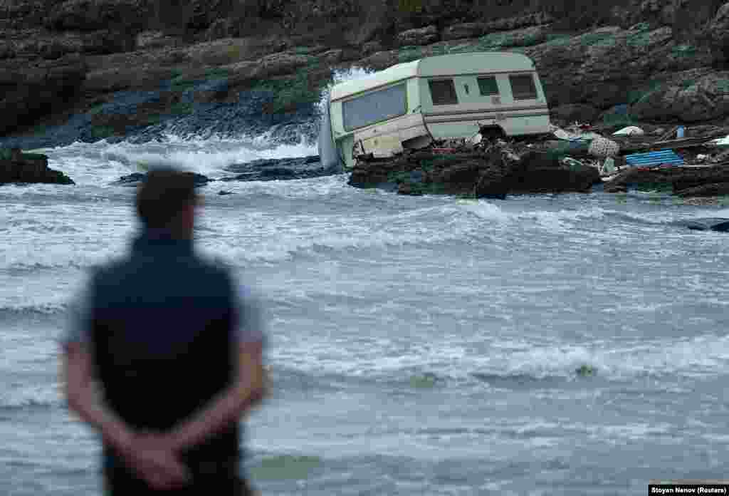 A man looks at a damaged caravan that was washed away by severe flooding. The missing mother and child were last seen in their car when the damaged bridge they were attempting to cross was swept out into the sea. 