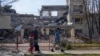 Residents of Ukraine's Kherson city walk past the building of the Kherson Academy of Continuing Education, which was destroyed by Russian attack UAVs. March 2024