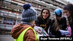 Dea Durmishi, e veshur me kostumin e superheroit Batman, i ofron një dhuratë një fëmije në oborrin e Klinikës së Pediatrisë në QKUK.