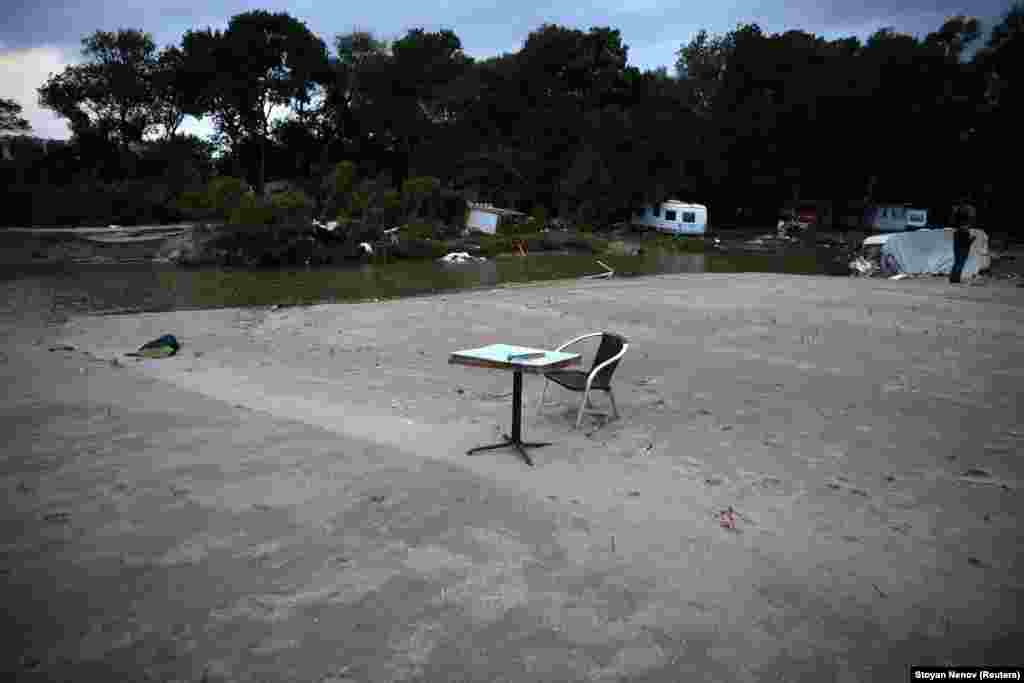 A table and chair near damaged caravans at a campsite. 