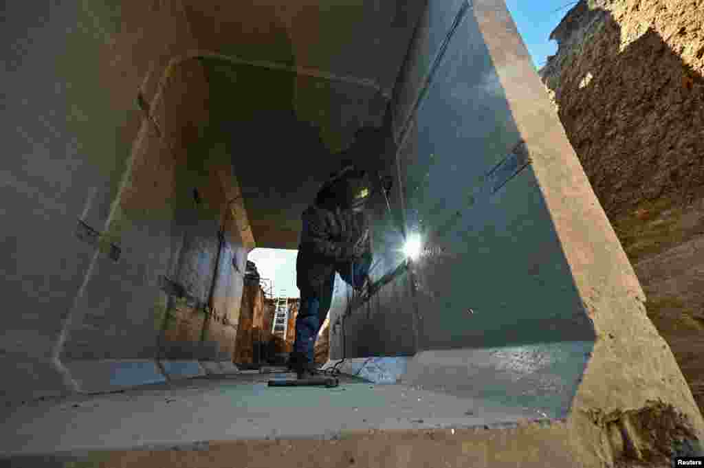 A worker welds inside a concrete dugout. "The situation is much better than it has been over the past three months," Zelenskiy said. 