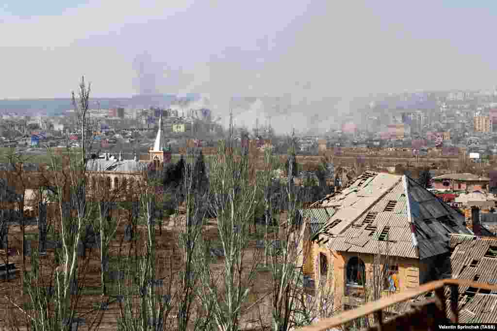 A view over Bakhmut taken from behind Russian lines in eastern Bakhmut on March 24. The image shows smoke rising from the center of the city. In the foreground is Bakhmut’s First Baptist Church, and a T-34 tank serving as a World War II memorial (visible at center left).