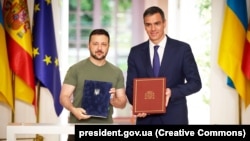 Ukrainian President Volodymyr Zelenskiy (left) and Spanish Prime Minister Pedro Sanchez pose for photos after signing a bilateral agreement on security cooperation in Madrid on May 27.