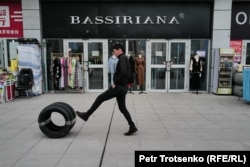 A man rolls a car tire past shops in Khorgos.