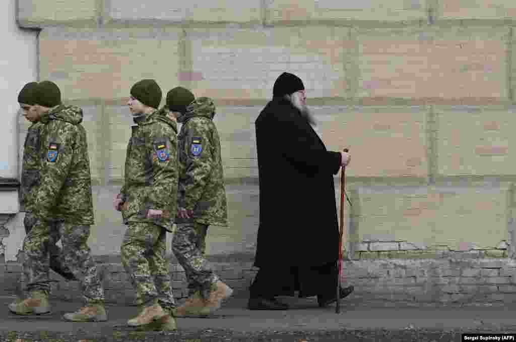 This March 14 photo shows Ukrainian soldiers passing a monk in the Kyiv Pechersk Lavra as tensions mount over a March 29 deadline for clerics to leave the property. The clergy have declared they will stay on in their historic home, as their supporters vow to back them “whatever the cost.” 