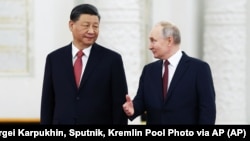 Russian President Vladimir Putin (right) speaks to Chinese President Xi Jinping as they attend an official welcome ceremony in Moscow on March 21.