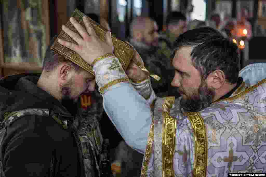 Ukrainian soldiers receive a blessing during Christmas Eve mass on December 24 near the city of Kupyansk in the Kharkiv region. Kyiv is defying Moscow as it celebrates Christmas for the first time on December 25 instead of on January 7, the day observed by the Russian Orthodox Church. 
