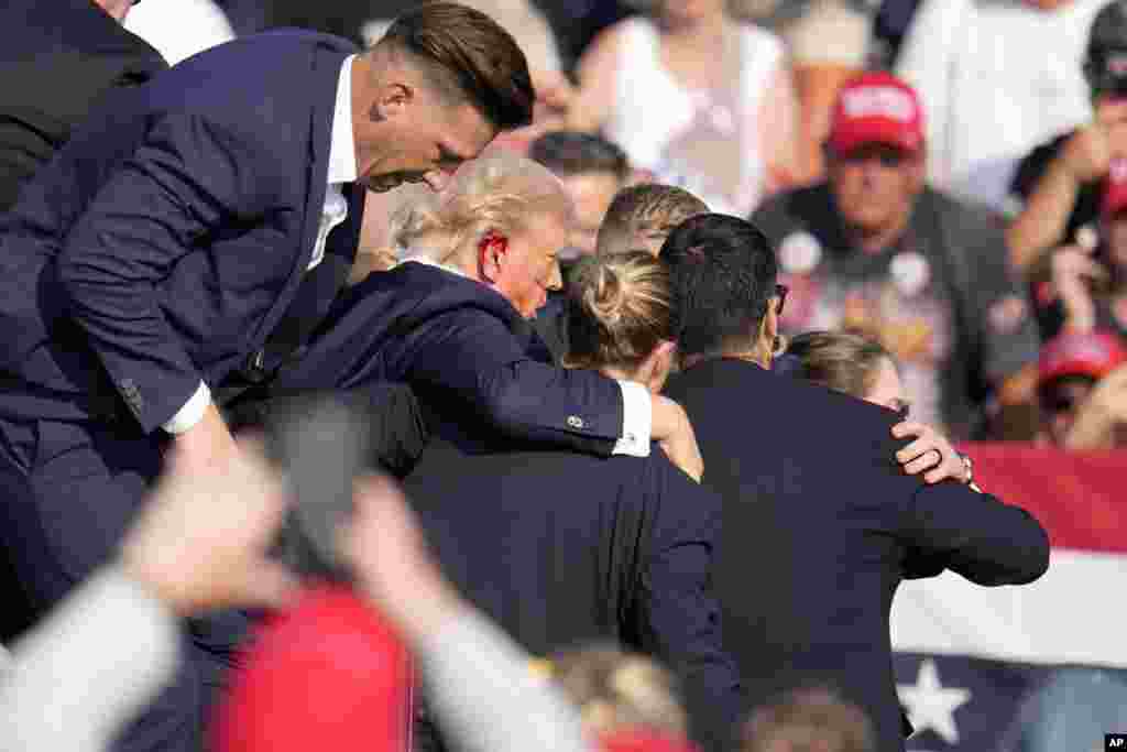 Blood was visible on Trump's right ear and cheek. He was whisked by the Secret Service agents into a waiting car and left the venue