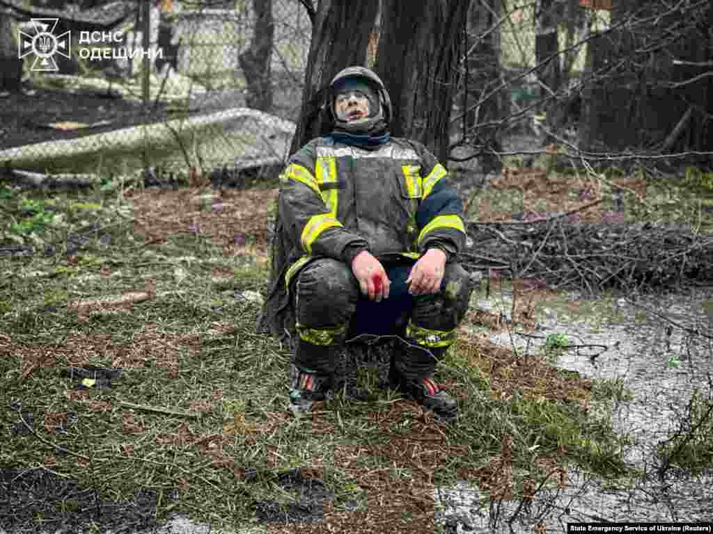 An injured rescuer sits under a tree following the attack that killed his comrades. Ukraine's State Emergency Service has been providing photography to international media outlets as they accompany the first responders.