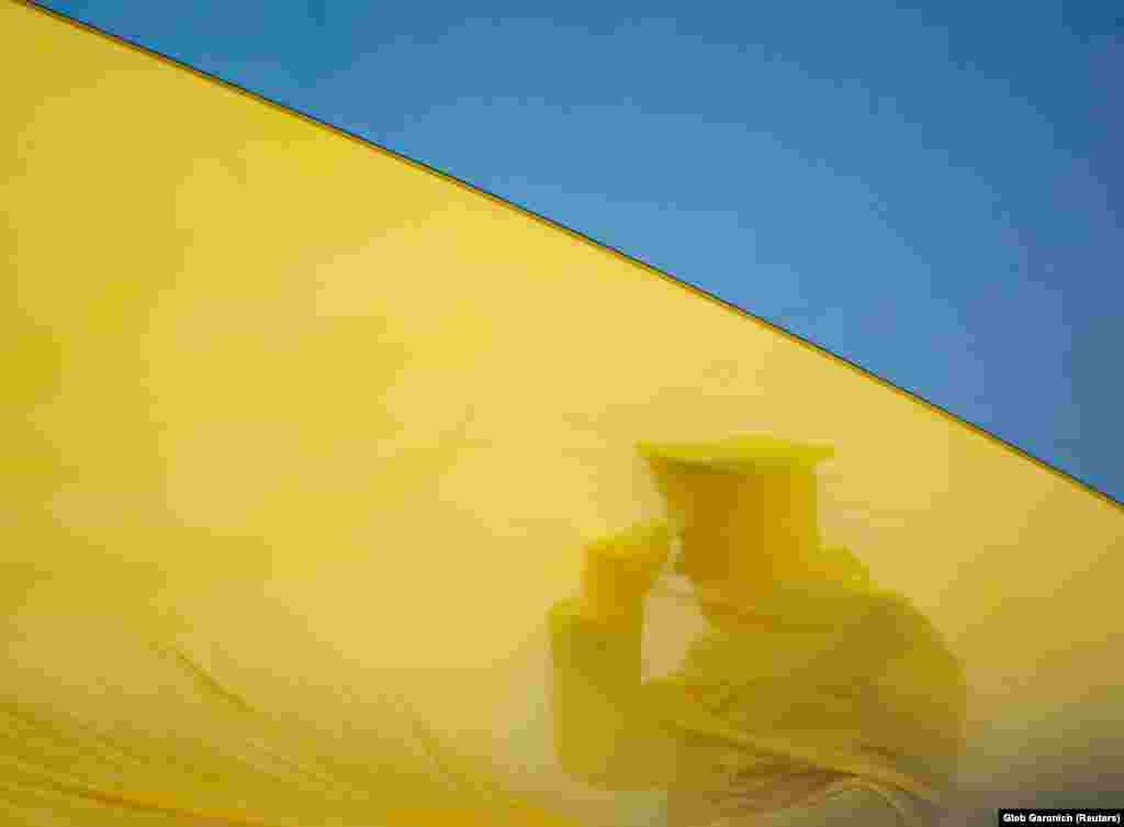 A member of the Honor Guard is seen as the Ukrainian national flag is hoisted during a ceremony to mark the first anniversary of the liberation of Bucha. President Volodymyr Zelenskiy said that Ukraine will never forgive the atrocities committed there.
