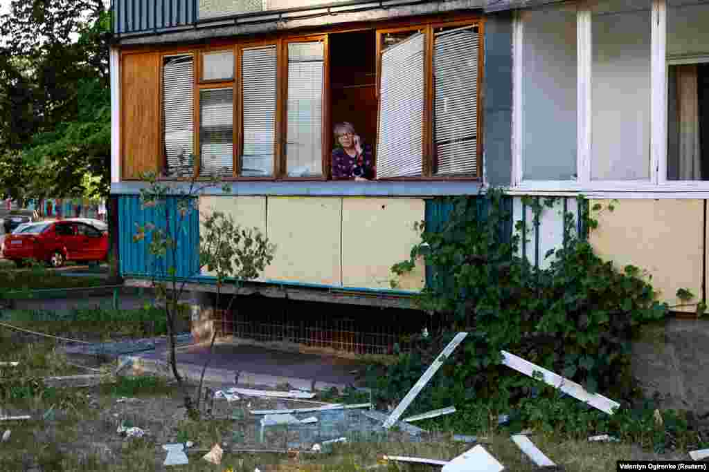 A woman whose apartment was damaged during the attack speaks on the phone as emergency responders work nearby. 