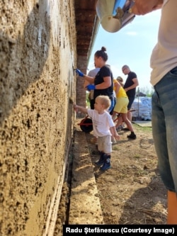Volunteers coat up the exterior of Casa Frusina.