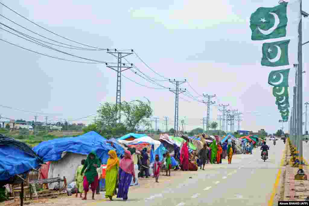 Flood-affected people walk past makeshift tents on a roadside after heavy monsoon rains in Hyderabad. Rain also triggered flash floods in the port city of Karachi, causing power outages, media reported. 