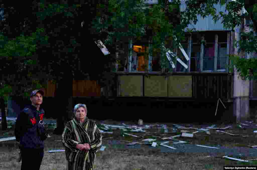 Residents stand near a damaged apartment building following the Russian missile attack on June 1. Police said a medical clinic, a kindergarten, residential buildings, and cars were damaged in the strike.