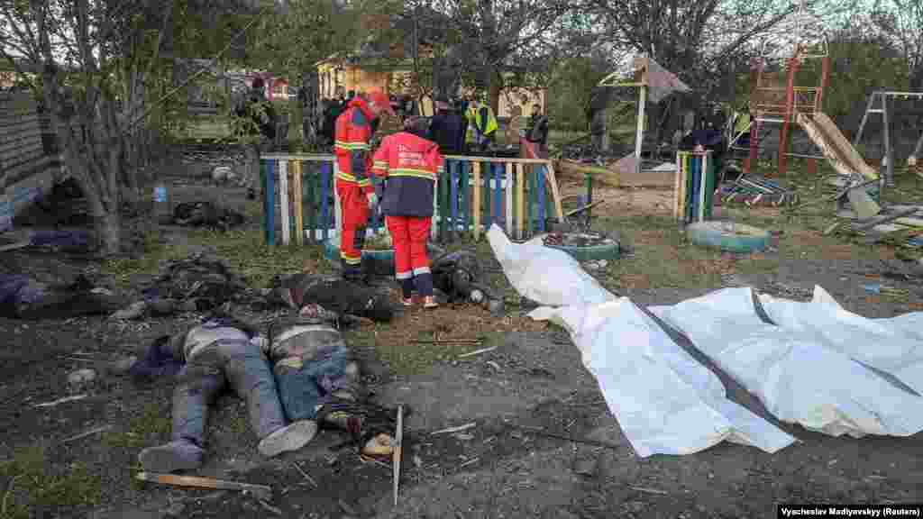 The bodies of victims lie scattered around a children's playground as firefighters and rescue workers survey the scene.