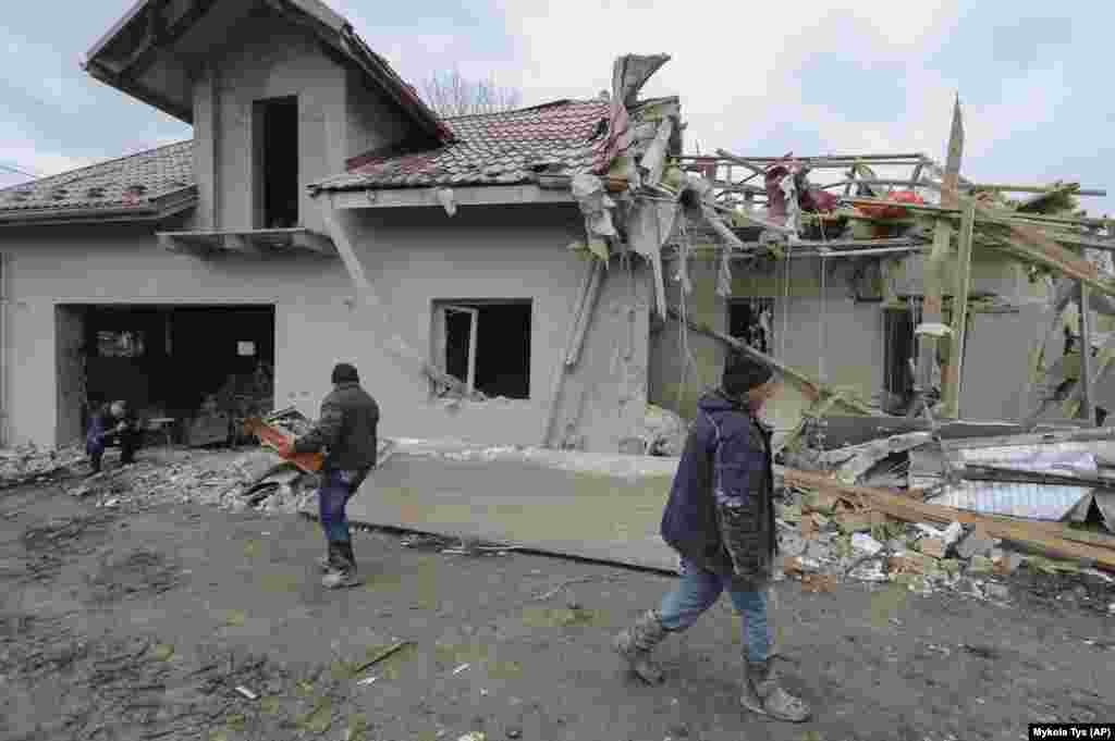 Villagers clear the rubble from a destroyed home in the village in Zolochevskiy. 