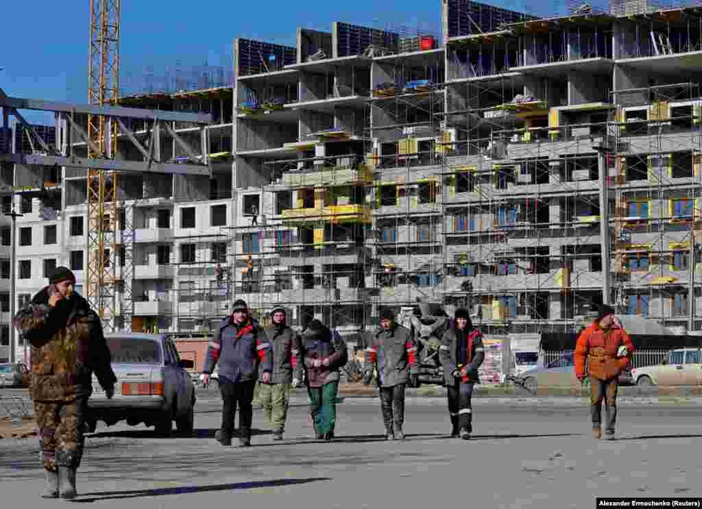 Workers at the site of a construction project in Mariupol. According to the UN, up to 90 percent of the city's residential buildings were damaged or destroyed during the Russian siege. 
