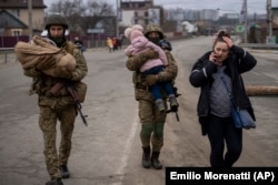 Ukrainian soldiers carry babies as they help a fleeing family to find a vehicle after crossing the Irpin River on the outskirts of Kyiv on March 5.