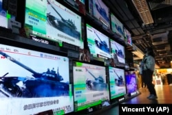 A woman in Hong Kong stands in front of TV screens broadcasting the news of Russia's invasion of Ukraine on February 24, 2022.
