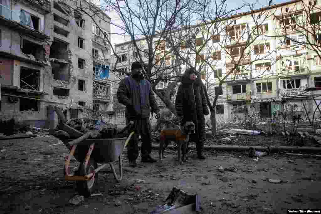 Bakhmut residents stand near a wheelbarrow used to collect firewood near their destroyed apartment. On December 6, the UN's humanitarian chief, Martin Griffiths, decried the "colossal" torment that Ukraine is suffering from Russia's destruction of its infrastructure.