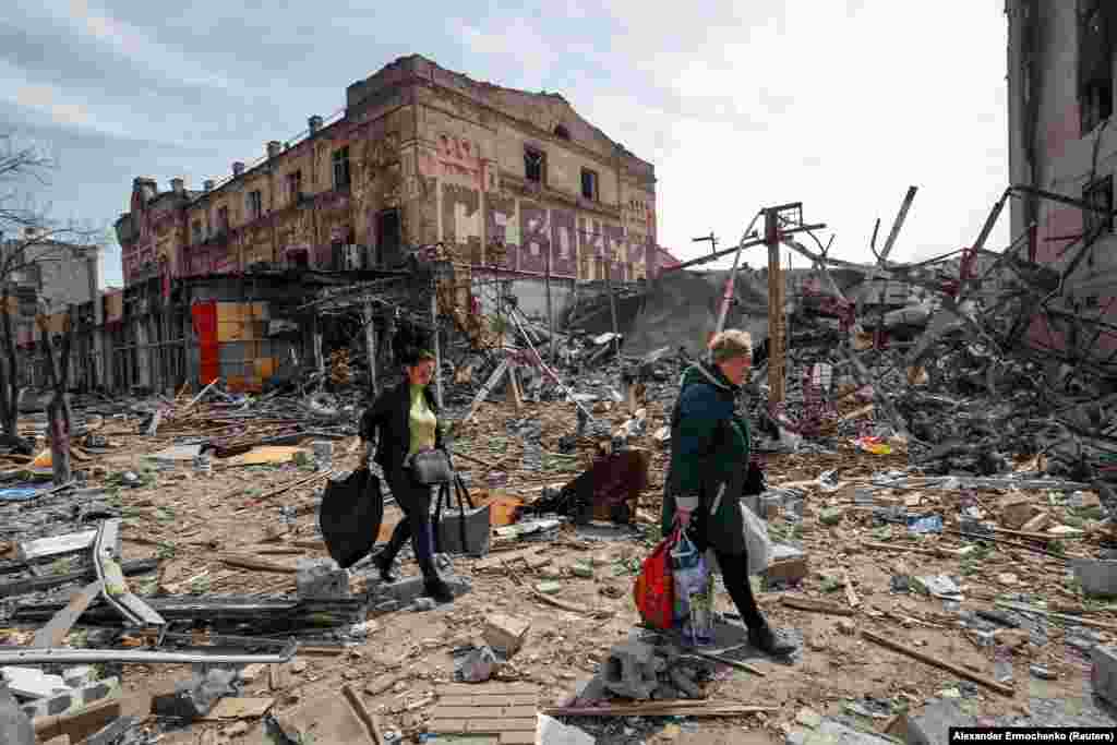 Residents of Mariupol carry their belongings past a destroyed building in the southeastern port city on April 10. 