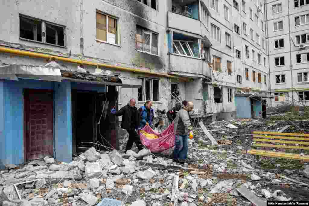 Emergency workers remove the body of a woman following an artillery attack that damaged an apartment block in Kharkiv on April 13. 