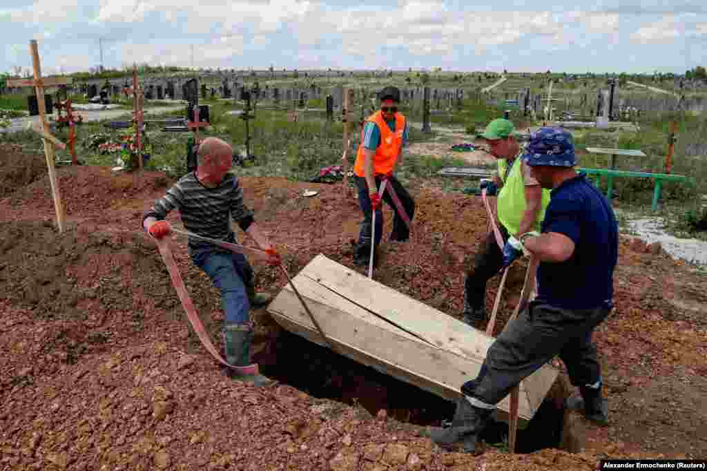 Gravediggers lower a simple wooden coffin into the ground in the Starokrymske cemetery in May. After the siege ended, satellite images showed the Mariupol cemetery rapidly expanding even months later, supposedly as bodies were recovered from the ruins of buildings in the Ukrainian port city. 