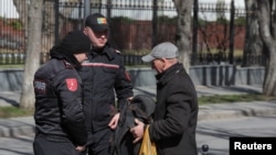 Moldovan police check a man's belongings during an anti-government protest in Chisinau on March 12.