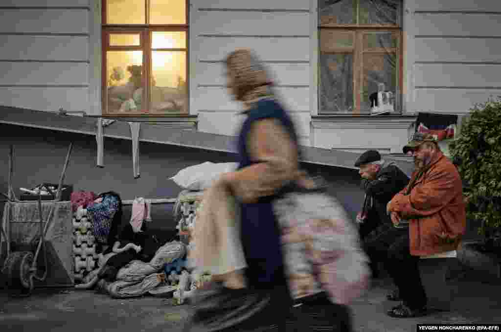 People stand next to a building near the Svyatohirsk Cave Monastery. According to Ukrainian authorities, the major Orthodox Christian monastery was damaged during Russian shelling of the town in June 2022.