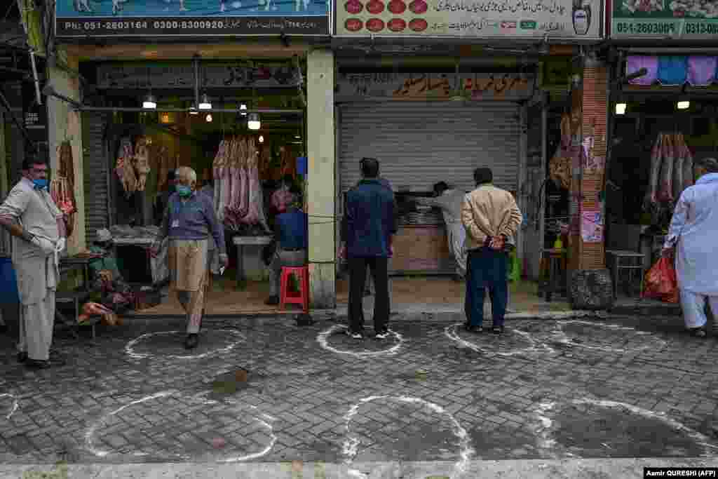 Customers stand in designated areas marked on the floor outside meat and grocery shops to maintain recommended social distancing during a government-imposed national lockdown as a preventive measure against the coronavirus in Islamabad on March 25.