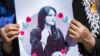 A woman holds a poster depicting Mahsa Amini during a protest following her death last year.