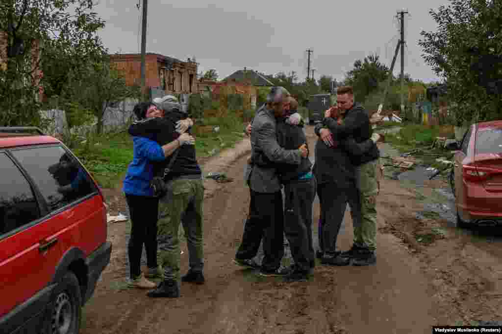 Neighbors embrace each others after they return to the liberated village of Kamyanka on October 2 in the Kharkiv region. 