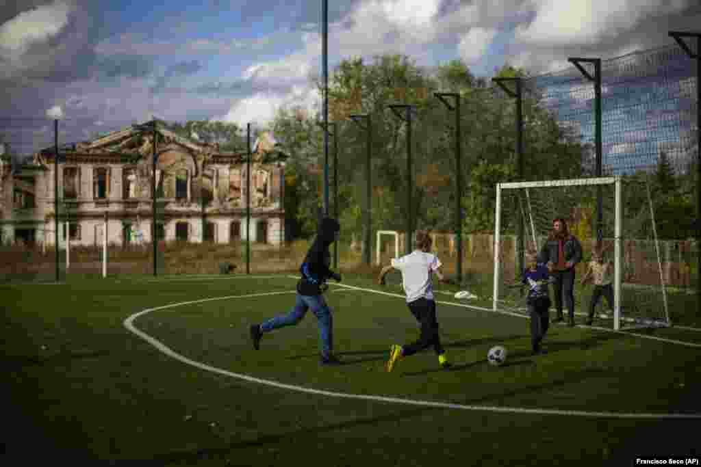 Boys play soccer next to a destroyed school in Izyum on October 3. After the city was recaptured from Russian forces in early September, a mass burial site with 440 graves was found and is being examined by experts.