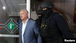 Ex-President Igor Dodon is escorted by law enforcement officers before a court hearing in Chisinau in May.
