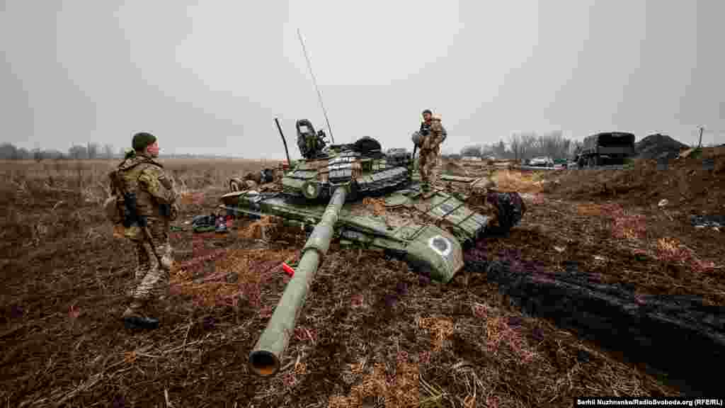 Ukrainian soldiers inspect a Russian tank stuck in the mud.