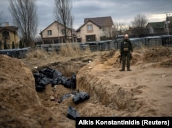 Fotografija od 6. aprila prikazuje ukrajinskog vojnika pored masovne grobnice civila ubijenih tokom uske okupacije Buče