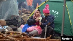 A migrant and her children rest beside a tent in Belarus's Hrodno region, near the Polish border, on November 10. 