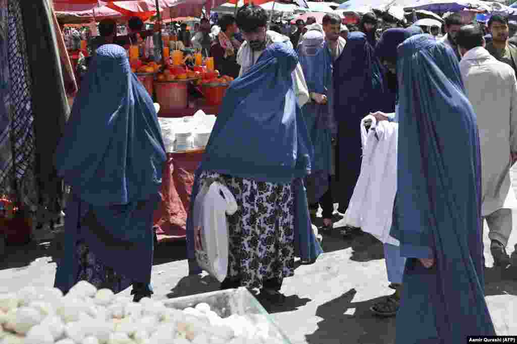 Burqa-clad women shop at a market in Kabul on August 28. Sales of all-encompassing burqas -- which were mandatory for women under the Taliban's previous regime -- have shot up in recent weeks. 