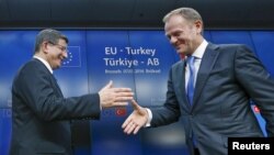 Turkish Prime Minister Ahmet Davutoglu (left) shakes hands with European Council President Donald Tusk after meeting to discuss Europe's migrant crisis. Turkey's neighbors fear that, if Ankara toughens its visa regime to help stem the flow of migrants into Europe, it could also drastically reduce the number of countries whose citizens can currently enter Turkey easily. 