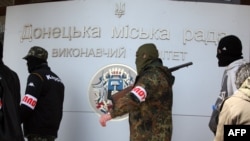 Armed pro-Russia activists walk outside the city state building they seized in the eastern Ukrainian city of Donetsk. So far, they have shown no sign of budging.